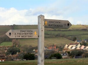 A wooden directional signpost with two arms pointing towards B. Freshwater and West Bay, and Burton Beach.