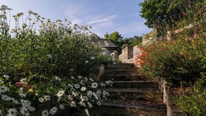 Eine Steintreppe, umgeben von üppigem Grün und weißen Blüten.