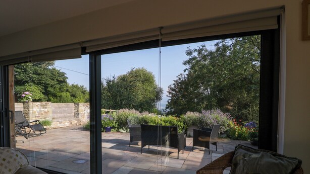 Ein Zimmer mit einer großen Schiebeglastür, die auf eine Terrasse im Freien führt.