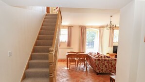 Eine Treppe führt zu einem Wohnbereich mit einer Couch, einem Esstisch und einem Kronleuchter.