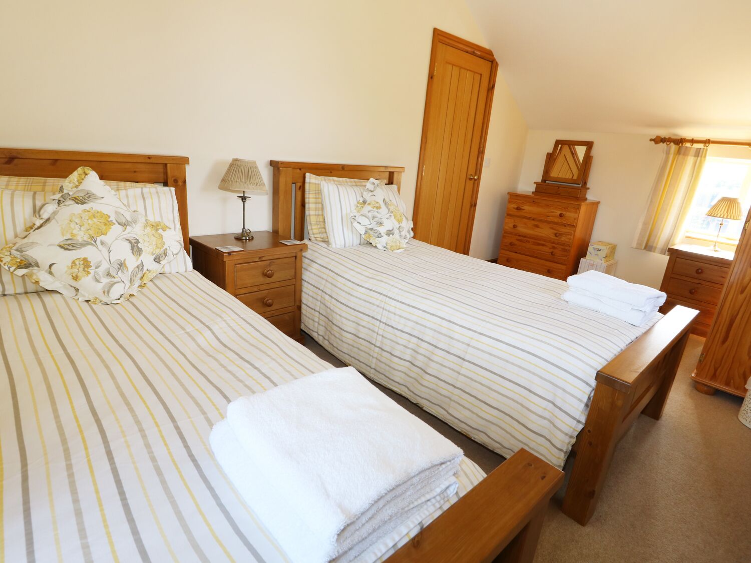 A double room with two beds, wooden headboards, bedside tables, a mirror, and a wardrobe.