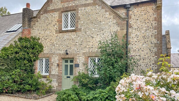 A traditional stone building with a green door, two windows, and a sign reading "The Old School House." - The Old School House (Dorchester)
