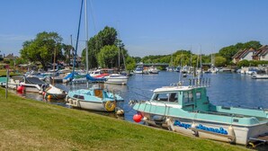 A marina with various boats docked, a grassy area in the foreground, and houses in the background. - 32 Cranleigh Close (Bournemouth)