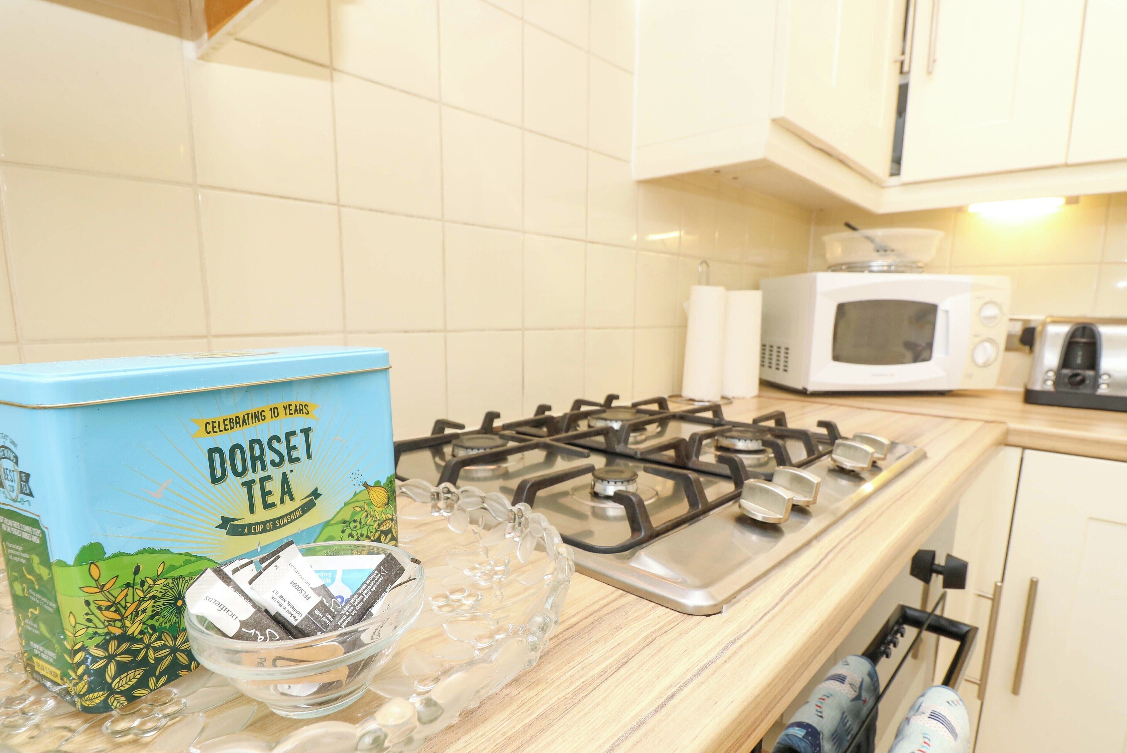 A kitchen with a gas stove, a microwave, and a tea box on the counter.