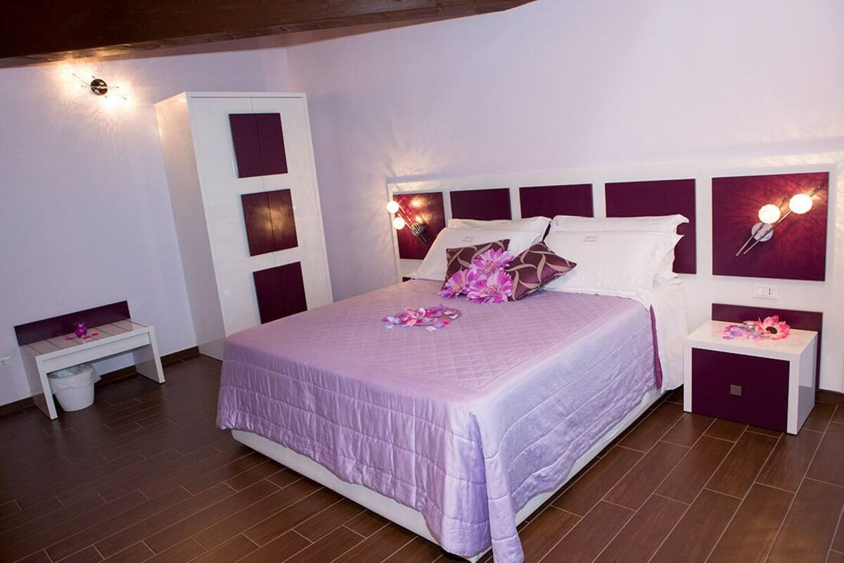 A bedroom with a bed, bedside tables, a wardrobe, and wall-mounted lights.
