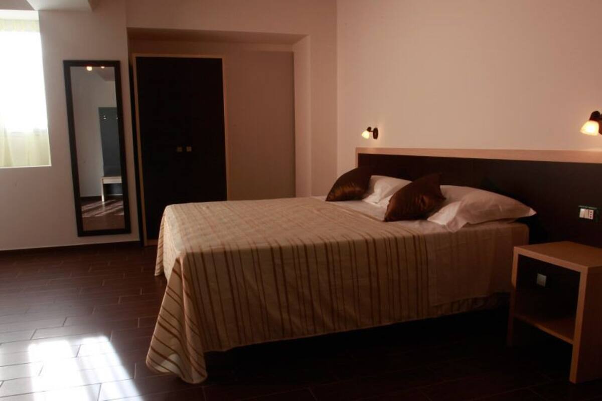 A bedroom with a bed, bedside table, and a mirror.