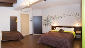 A bedroom with two beds, a wardrobe, a small table, and a wall decoration. - Parco delle Stelle (Castelmauro)