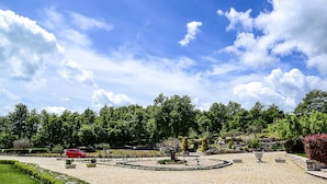 A landscaped garden with a circular stone pathway, a red car, and a bench. - Parco delle Stelle (Castelmauro)