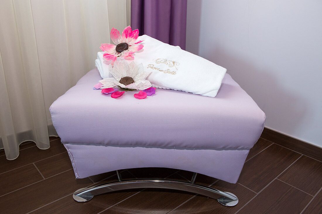 Un petit tabouret rembourré, sur lequel sont posés une serviette blanche et quelques fleurs décoratives.