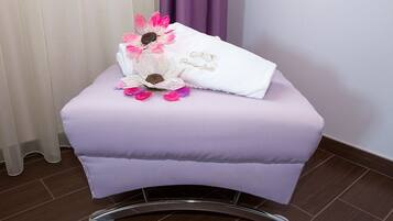 Un petit tabouret rembourré, sur lequel sont posés une serviette blanche et quelques fleurs décoratives.