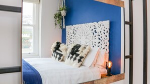 A bedroom with a bed, decorative headboard, and a bedside table with a lamp. - Seasound (Ilfracombe)