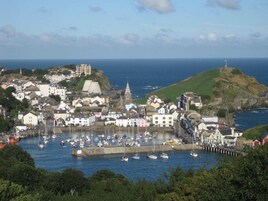 Un pueblo costero con un puerto lleno de barcos, edificios históricos y una iglesia destacada.