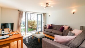 A living room with a sofa, a dining table with plates and glasses, and a TV. - Admiral's Retreat (Weymouth)