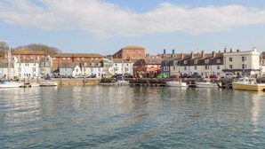 A harbor with boats docked, buildings along the waterfront, and a clear sky. - Admiral's Retreat (Weymouth)
