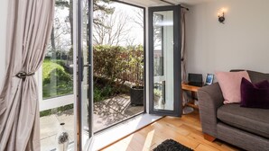 A modern living room with a sliding glass door leading to a garden. - Admiral's Retreat (Weymouth)