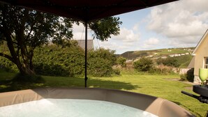 Un jacuzzi con vistas a un jardín césped y una casa al fondo.