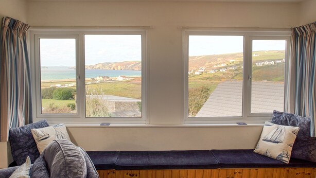 Una habitación con un banco de madera a lo largo de una pared con dos ventanas que ofrecen vistas de un paisaje costero.