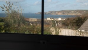 Un paisaje costero con vista al mar, zonas cubiertas de hierba y un muro de piedra.