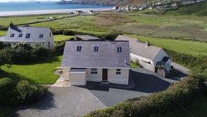Una propiedad costera con varias casas, un camino de acceso y vistas a la playa y los acantilados.