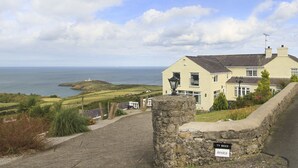 A coastal house with a stone wall and a sign reading "TY BRICS Amolca". - Amolca (Amlwch)