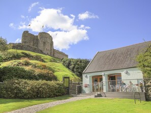 A stone castle on a hill with a building in the foreground. - Cennin (Criccieth)