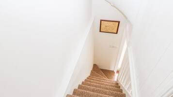 A staircase with carpeted steps leading up to a landing with a framed picture on the wall.