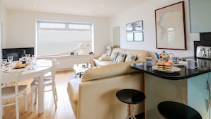 A modern living room with a sofa, a dining table set for two, and a kitchen area with a toaster. - The View (Portland)