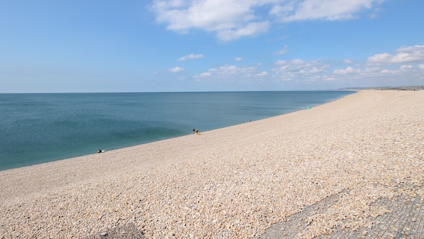 A wide, pebbled beach with a clear sky and calm sea. - The View (Portland)