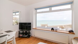 A modern room with a large window offering a view of the sea, a television, a dining table, and a comfortable seating area. - The View (Portland)