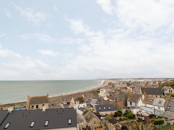 Eine Küstenstadt mit Häusern direkt am Strand, bewölkter Himmel und Blick auf das Meer.