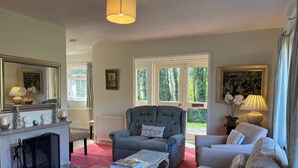 A living room with a fireplace, a grey armchair, a white sofa, and a coffee table. - Woodlands Cottage (Dorchester)