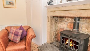 Ein gemütliches Wohnzimmer mit Ledersessel, Kamin mit Steinwand und Kaminabdeckung mit Dekoration.