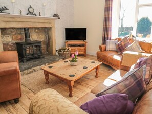 Un salón acogedor con chimenea, televisor y asientos cómodos.