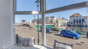 A room with a large window offering a view of a street with cars and buildings.