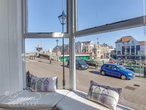 A room with a large window offering a view of a street with cars and buildings.