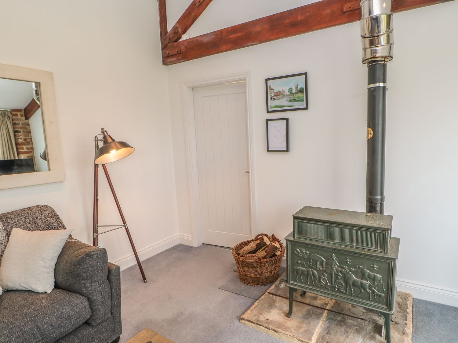 A cozy room with a green wood-burning stove, a floor lamp, a sofa, and a door.