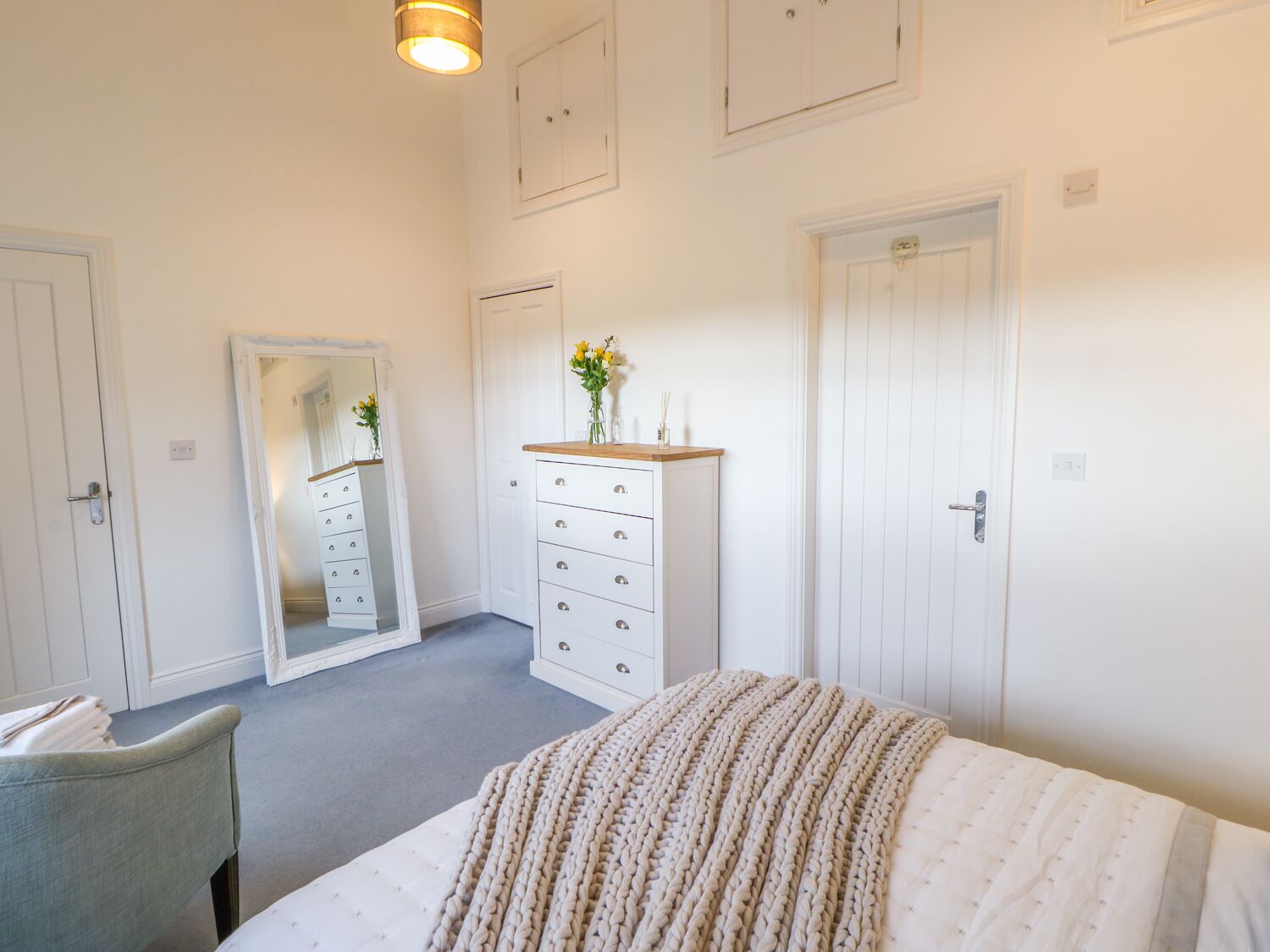 A bedroom with a bed, a dresser, a mirror, and a door.