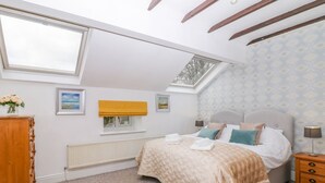 Ein Schlafzimmer mit Bett, Nachttischen, Heizkörper, Fenster und Dachfenster.