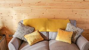 A grey sofa with three cushions in a wooden cabin room. - Dingle Den (Hereford)