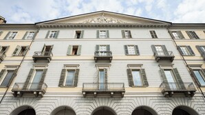 Ein mehrstöckiges Gebäude im klassischen Stil, mit Rundbogenfenstern und Balkonen.