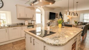 Une cuisine moderne avec des meubles blancs, un plan de travail en granit et une cuisinière intégrée.