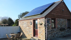 Ein Gebäude aus Stein mit geneigtem Dach und Solaranlagen.