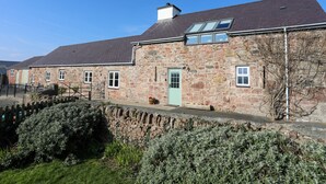 A stone building with a green door, multiple windows, and a sloped roof.