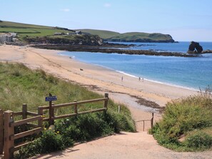 A coastal beach with a wooden fence and a sign indicating no parking. - Savernake (Kingsbridge)