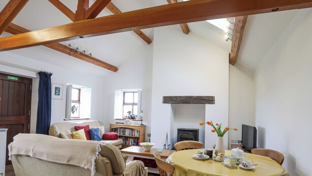 A cozy living room with a sofa, a wooden table, and a fireplace.