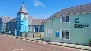 A heritage building with a blue facade and a tower, labeled as CEMAES Heritage Centre. - Farm Cottage (Cemaes Bay)