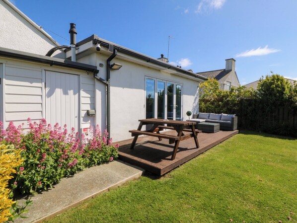 A house with a patio, a garden with flowers, and a lawn. - Farm Cottage (Cemaes Bay)