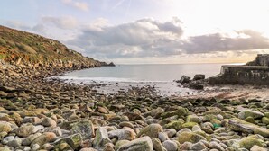 A rocky beach with a stone wall and a cliff. - Meadowside (Penzance)