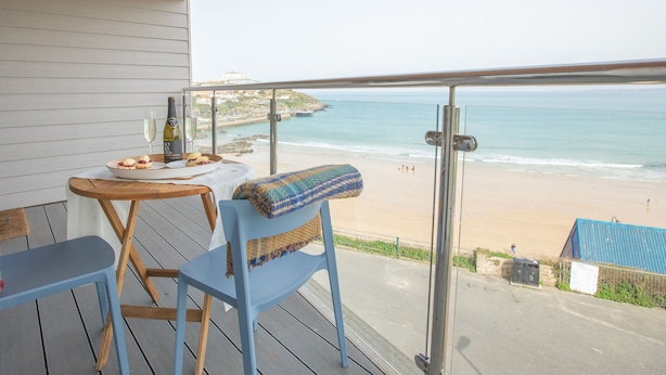 Un balcón con mesa y sillas, con vista a la playa.