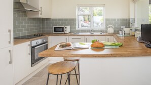 A modern kitchen with a central island, stainless steel appliances, and a view of the outdoors. - Frondeg (Bangor)